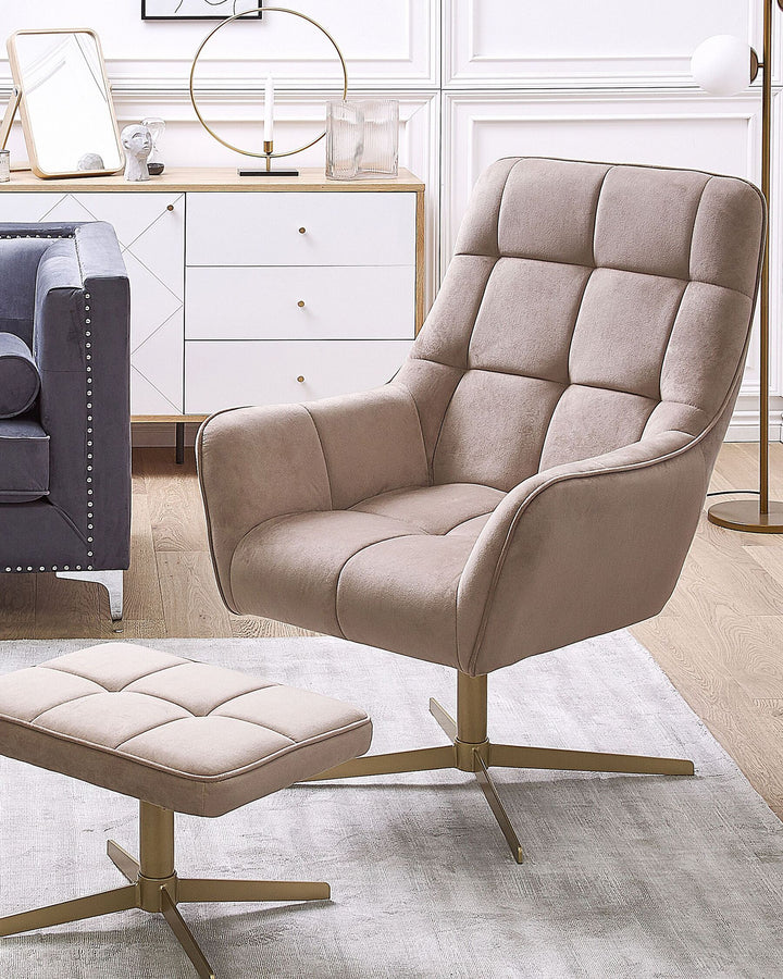 A beige velvet armchair with gold metal legs, accompanied by a matching footstool, set against a modern interior background.