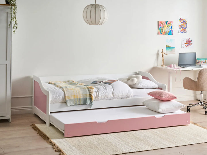 White and pink bed with a pull-out drawer in a room with a desk and decor.