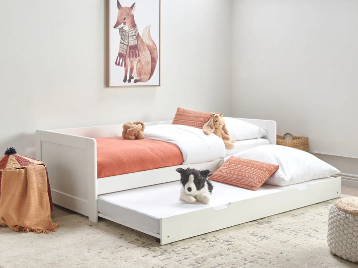 Children's bedroom with a white bed and pull-out trundle, featuring teddy bears and a dog.