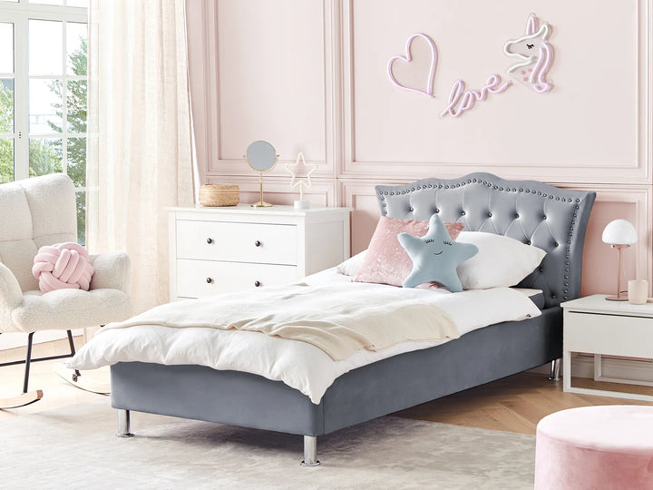 Children's bedroom with a gray upholstered bed, pink walls, and decorative elements.