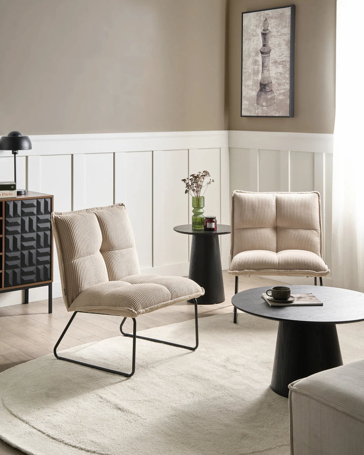 Modern living room with beige armchairs, a round coffee table, and decorative elements.
