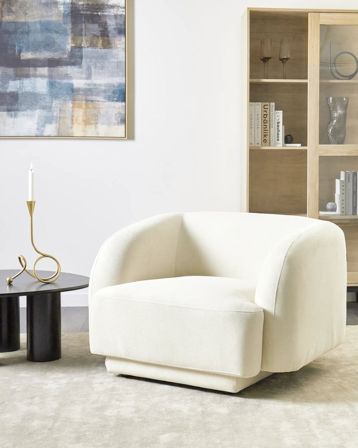 White armchair in a living room with a bookshelf and abstract painting.
