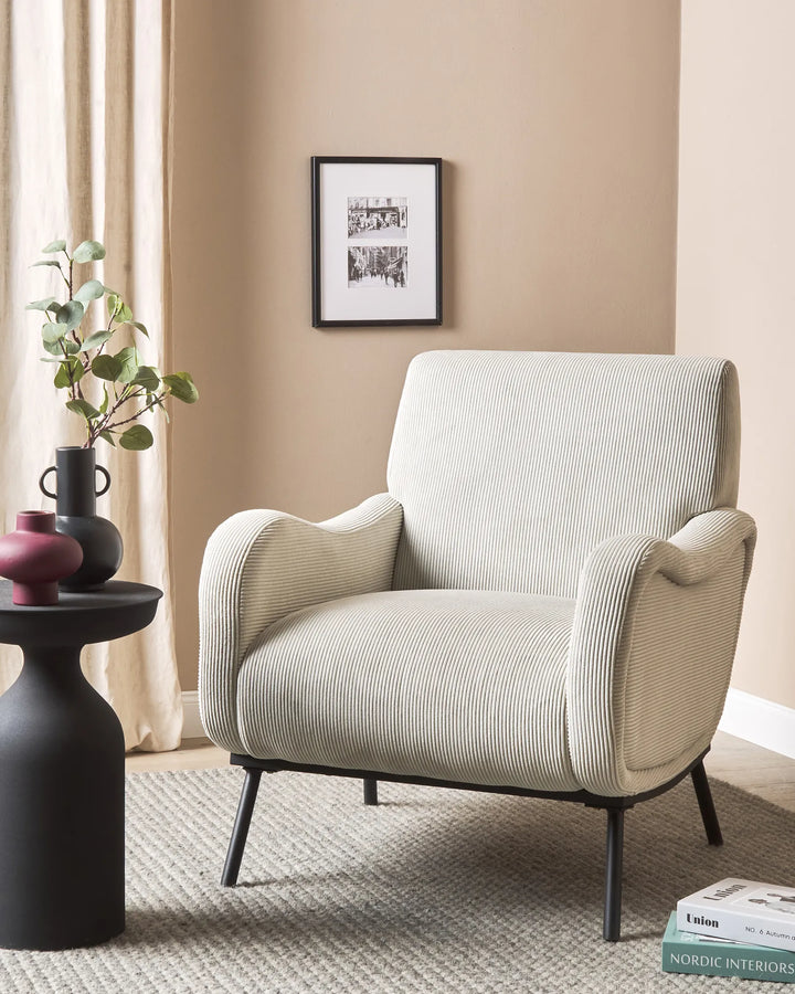 Beige armchair in a living room with a side table and decor items.