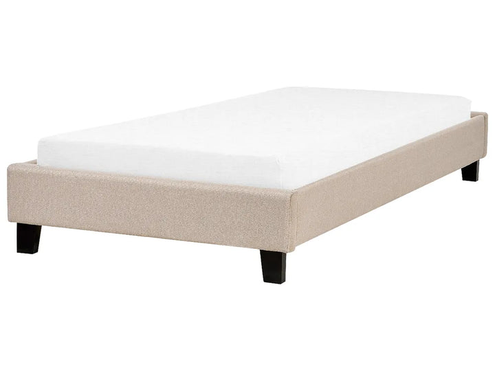 Beige upholstered bed frame with white mattress on a white background