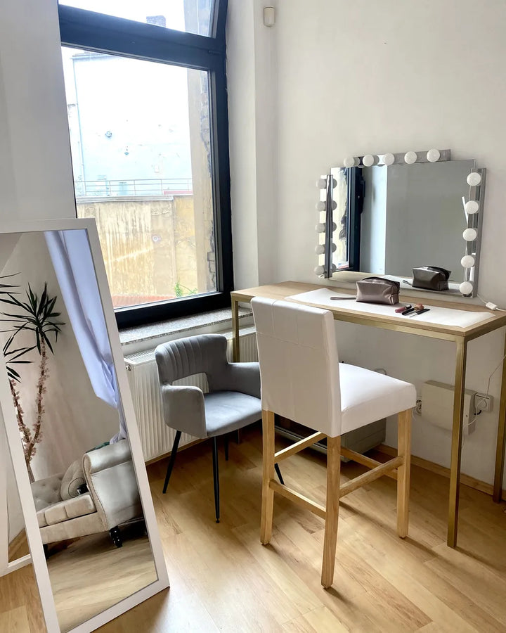 Dressing table with mirror and chair in a room with large windows.