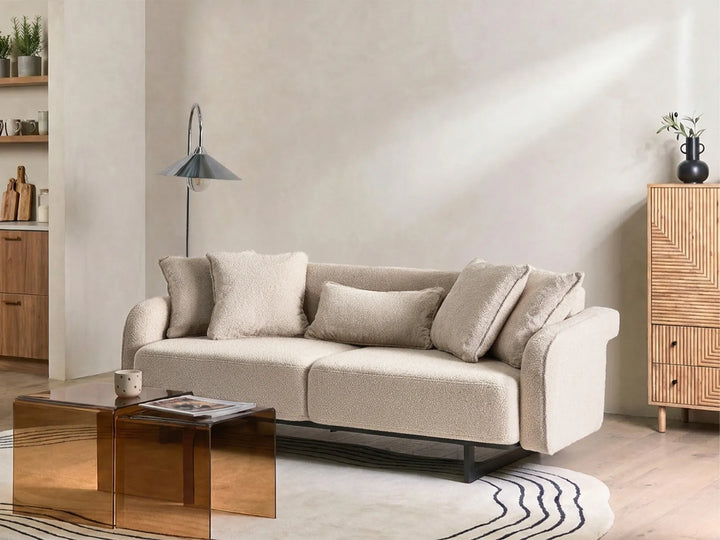 Beige sofa in a living room with a metallic coffee table and wooden cabinet.