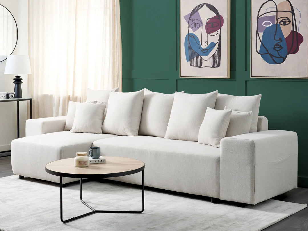 White sectional sofa in a living room with abstract art on the wall.