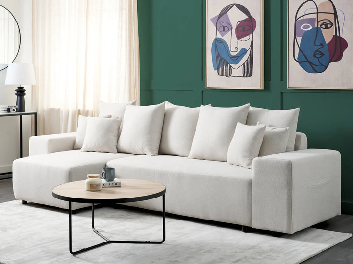 White sectional sofa in a living room with abstract art on the wall.