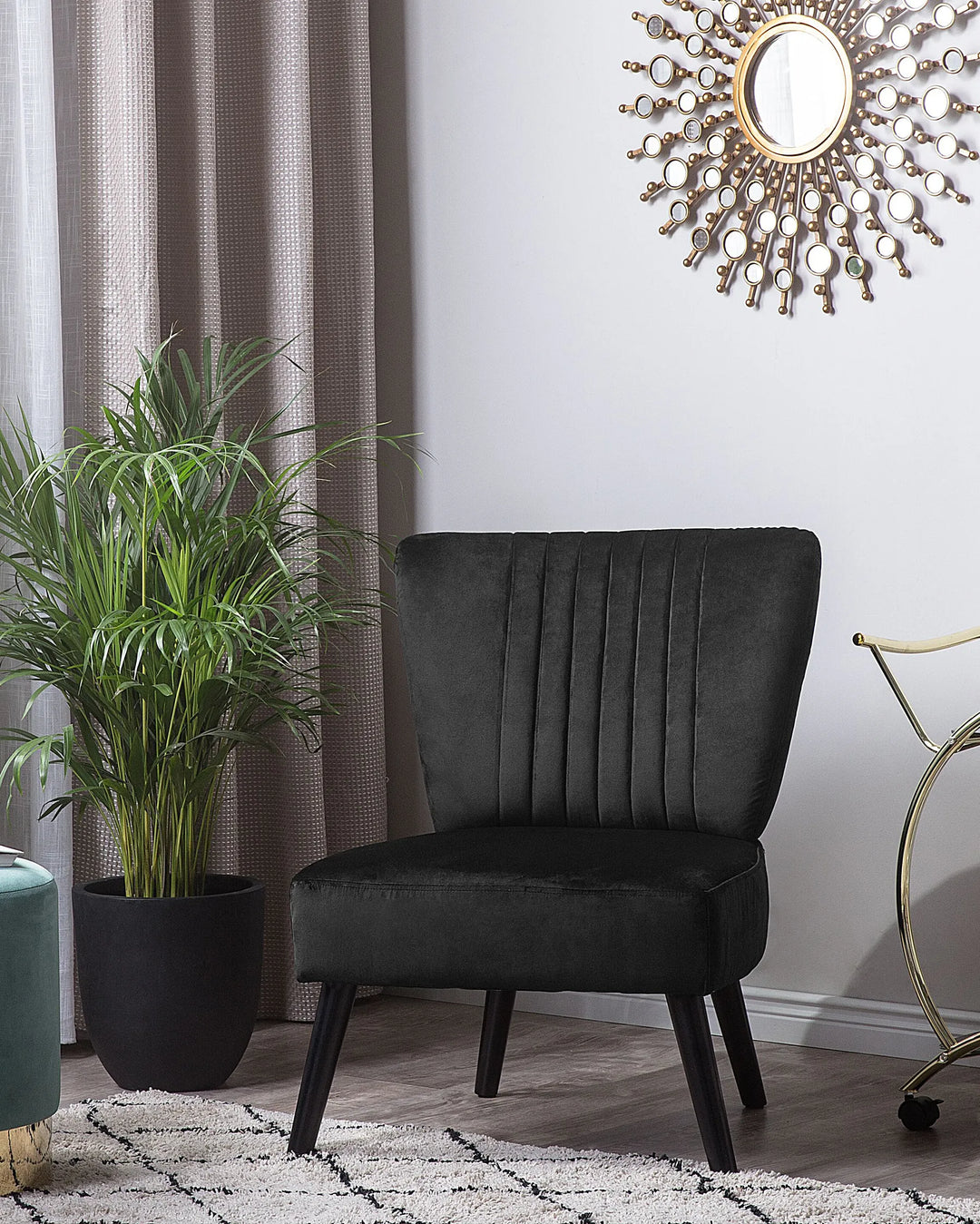 Black upholstered chair in a room with a plant, curtain, and decorative wall clock.