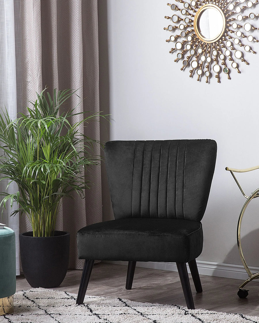 Black upholstered chair in a room with a plant, curtain, and decorative wall clock.