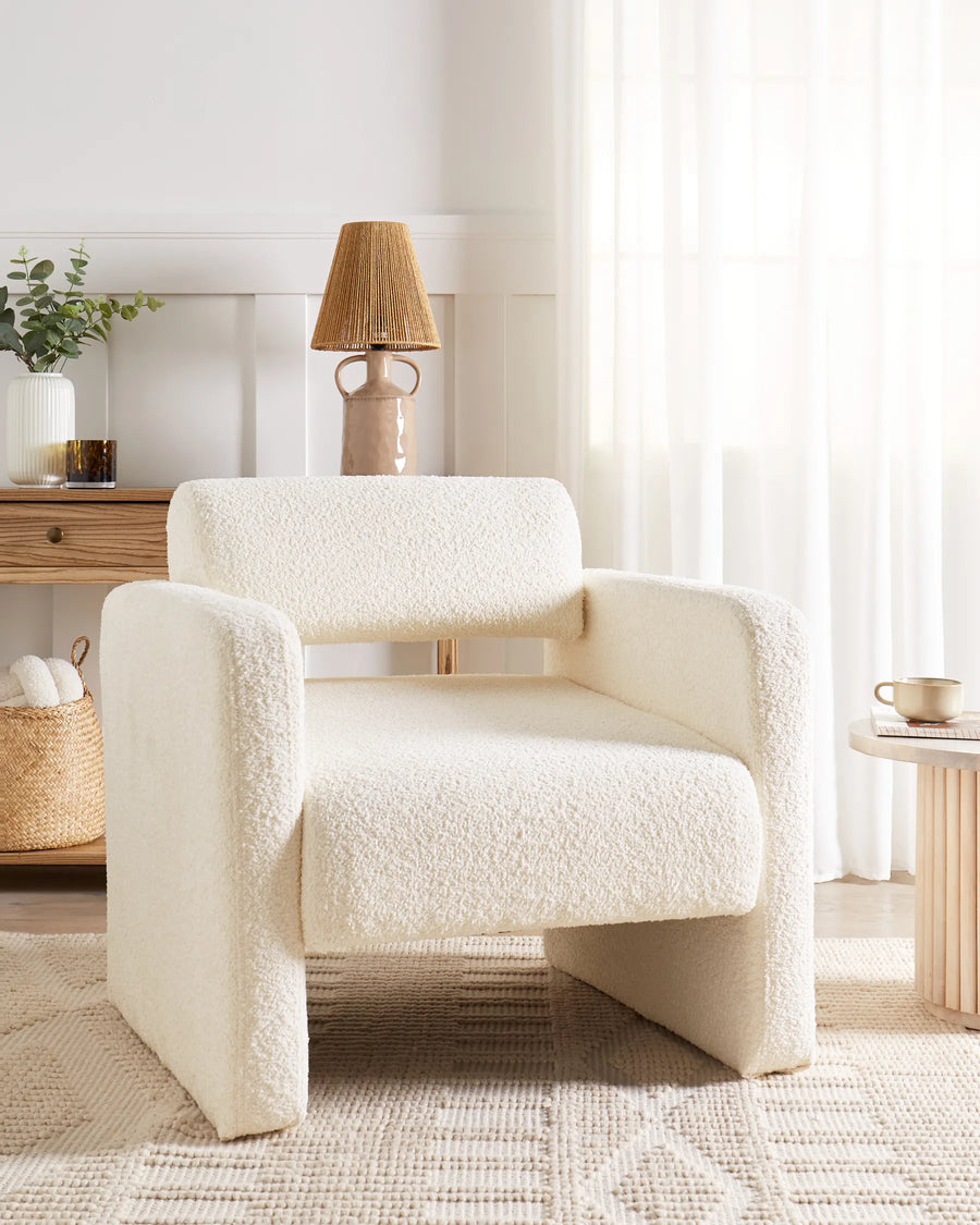 White textured armchair in a bright living room with a lamp and decor items.