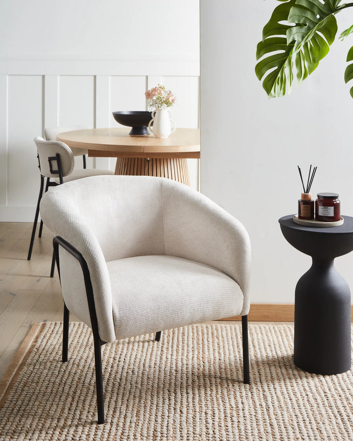 Modern white armchair in a room with a dining table and decor items.