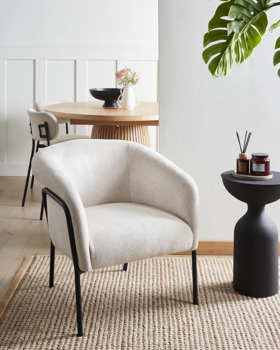 Modern white armchair in a room with a dining table and decor items.