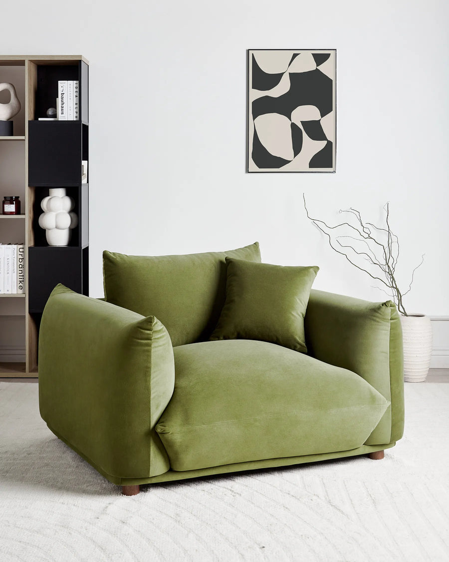 Green sofa in a modern living room with abstract art and bookshelf.