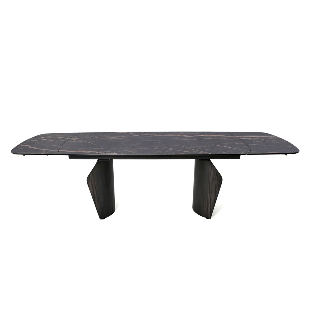 A modern rectangular dining table with a dark black marble top featuring subtle light veining, supported by two sculptural dark wood legs, shown against a plain white background.