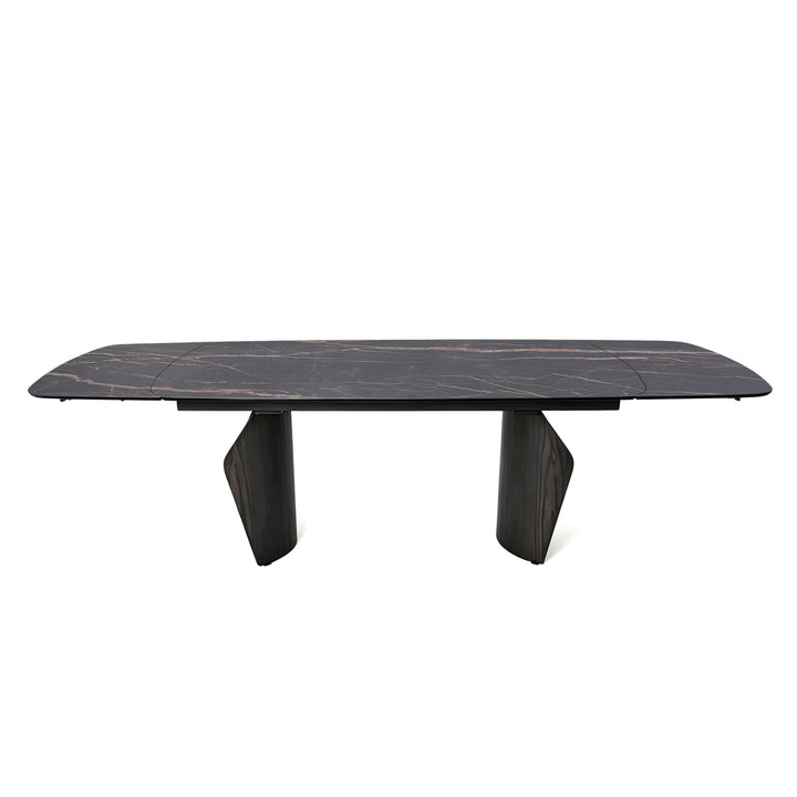 A modern rectangular dining table with a dark black marble top featuring subtle light veining, supported by two sculptural dark wood legs, shown against a plain white background.