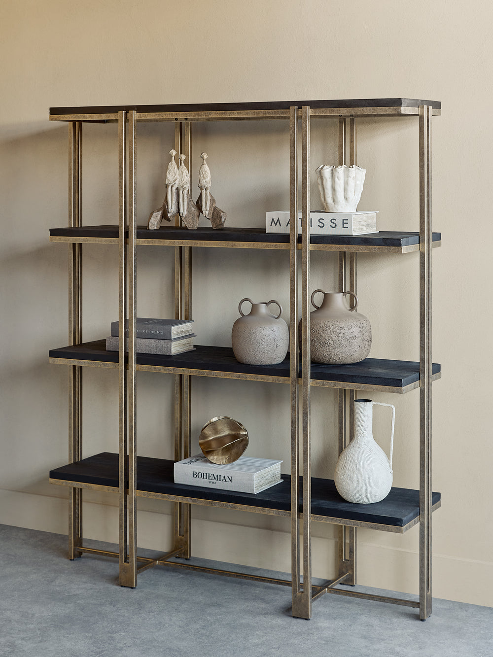 Decorative shelf with black shelves and gold metal frame against a beige wall.