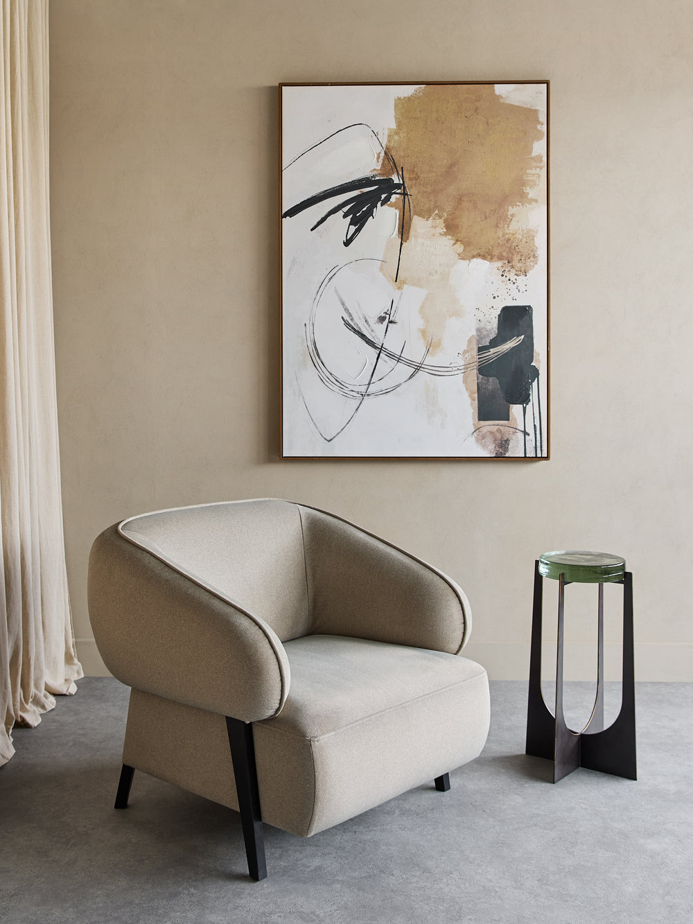 Beige armchair in a room with abstract art and a side table.