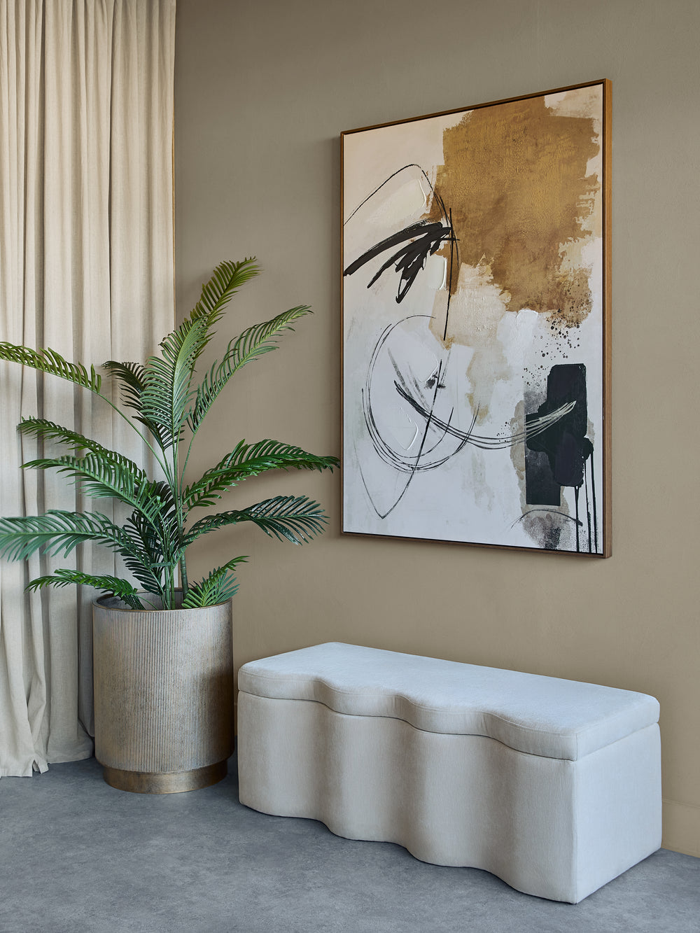 Modern interior with abstract art, plant, and wavy bench against a beige wall.