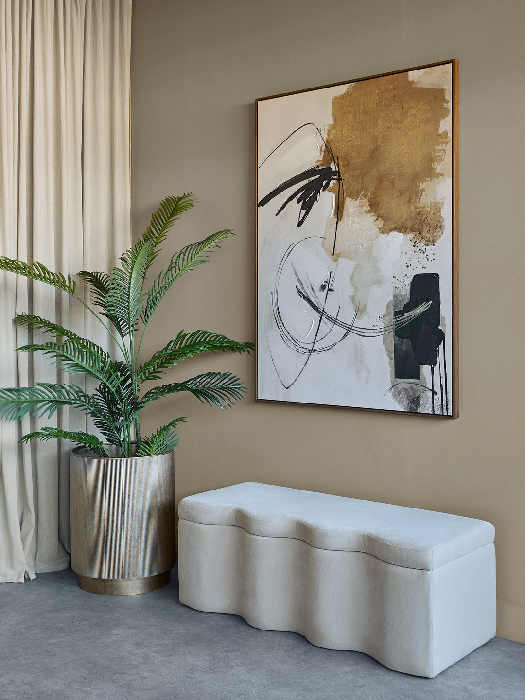 Modern interior with abstract art, plant, and wavy bench against a beige wall.