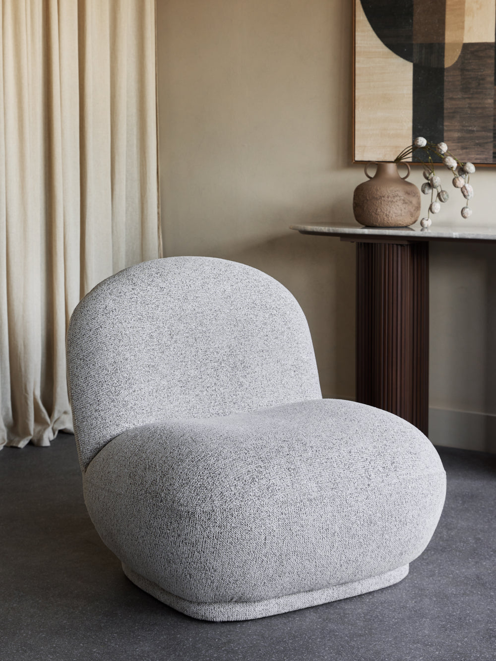 Gray textured armchair in a room with beige walls and a side table.