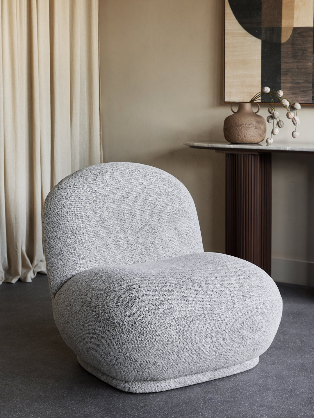 Gray textured armchair in a room with beige walls and a side table.