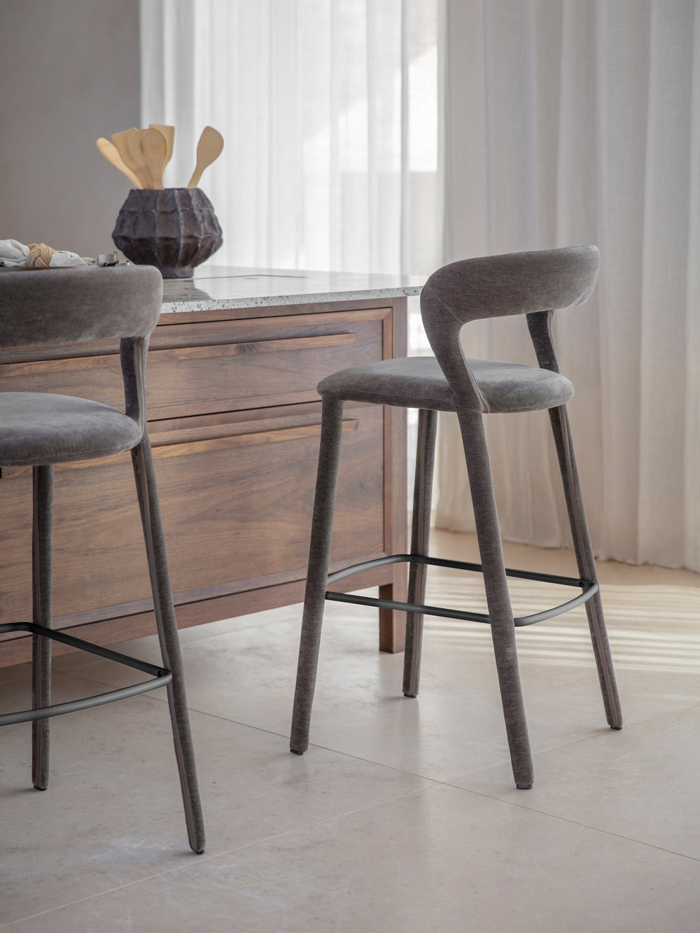 Two gray bar stools in front of a wooden cabinet with a marble countertop.