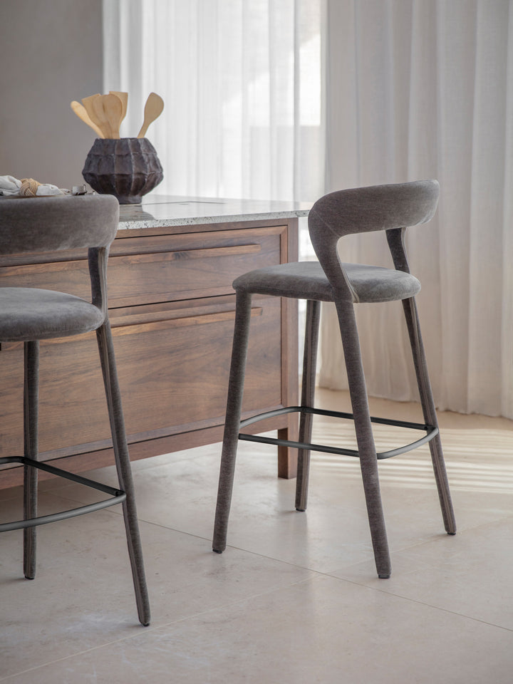 Two gray bar stools in front of a wooden cabinet with a marble countertop.