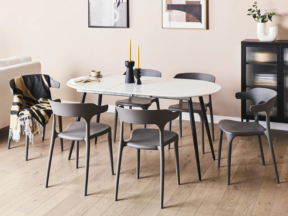 Dining room with a white oval table and gray chairs on a wooden floor.