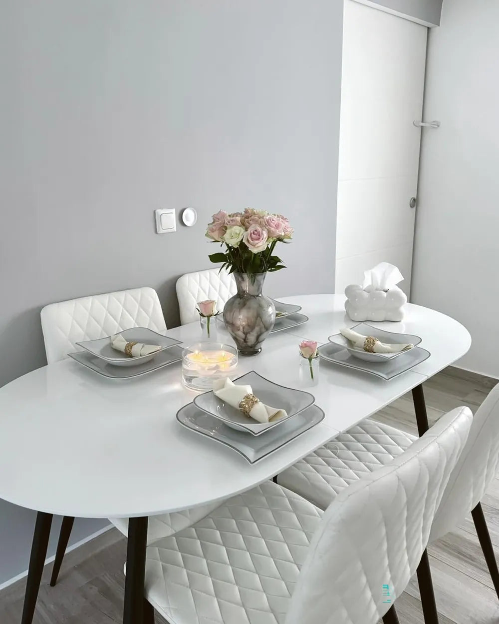 Dining table set with plates, napkins, and a vase of flowers in a modern kitchen.