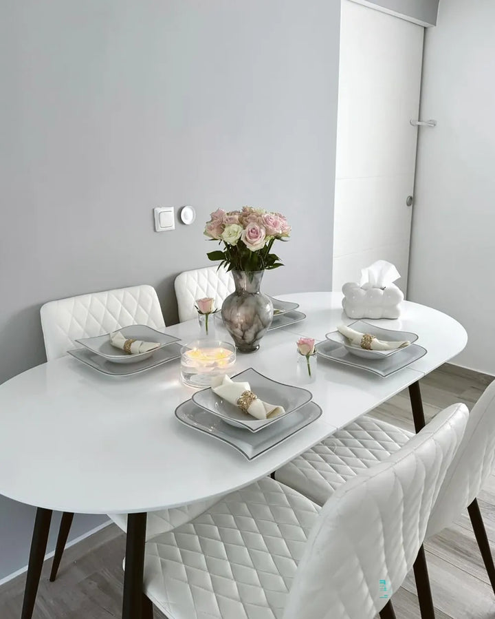 Dining table set with plates, napkins, and a vase of flowers in a modern kitchen.