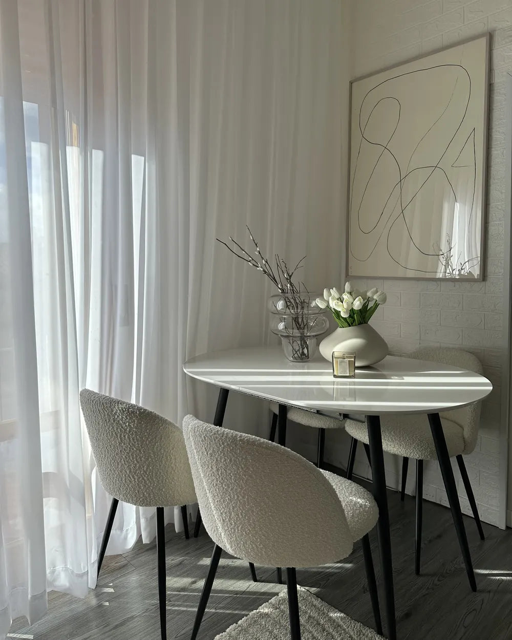Modern dining area with a white marble table and chairs, featuring abstract art on the wall.