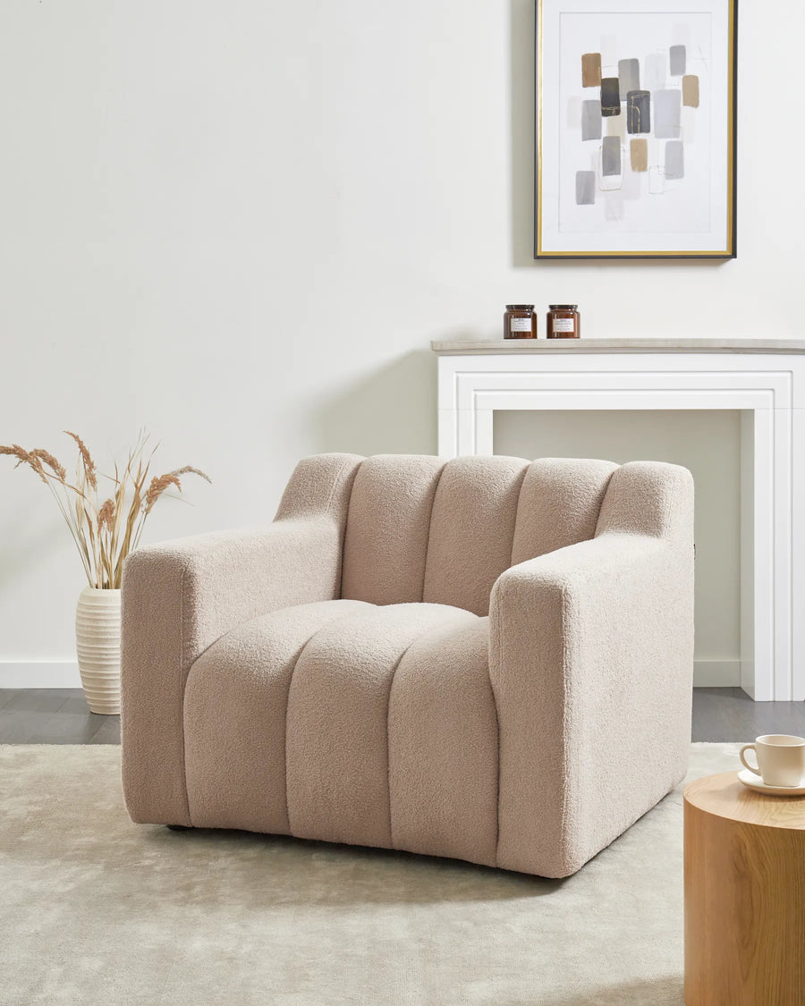 Beige armchair in a living room setting with a fireplace and decor elements.