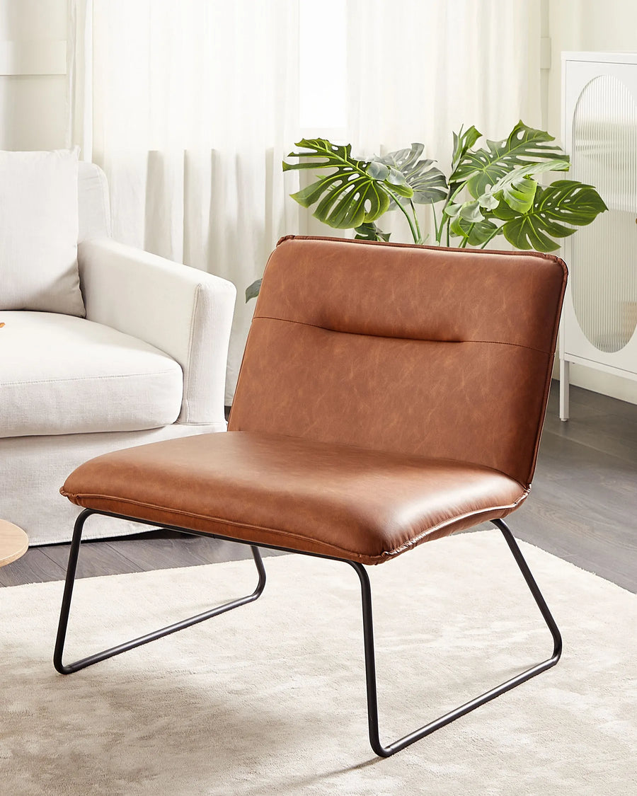 Brown leather chair in a modern living room with white sofa and plants.