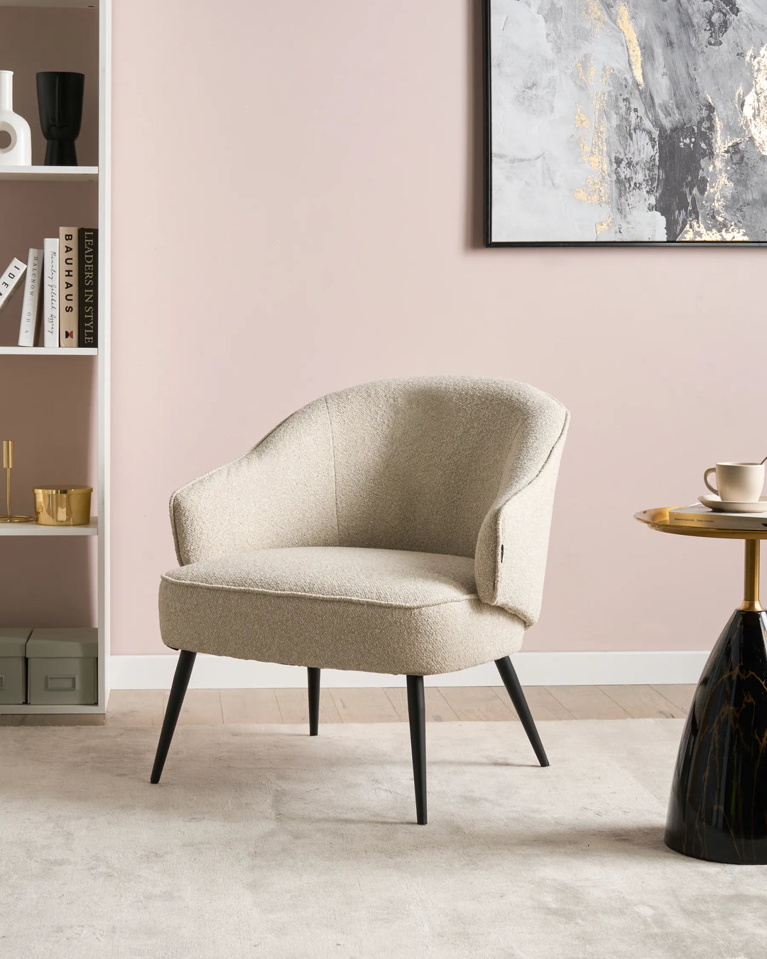Beige armchair in a room with a pink wall, bookshelf, and side table.