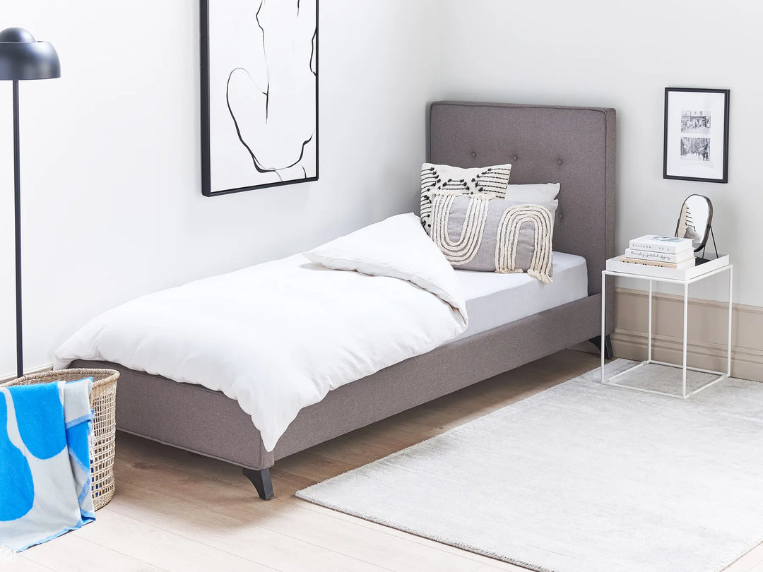 Modern bedroom with a gray upholstered bed, white bedding, and decorative pillows.