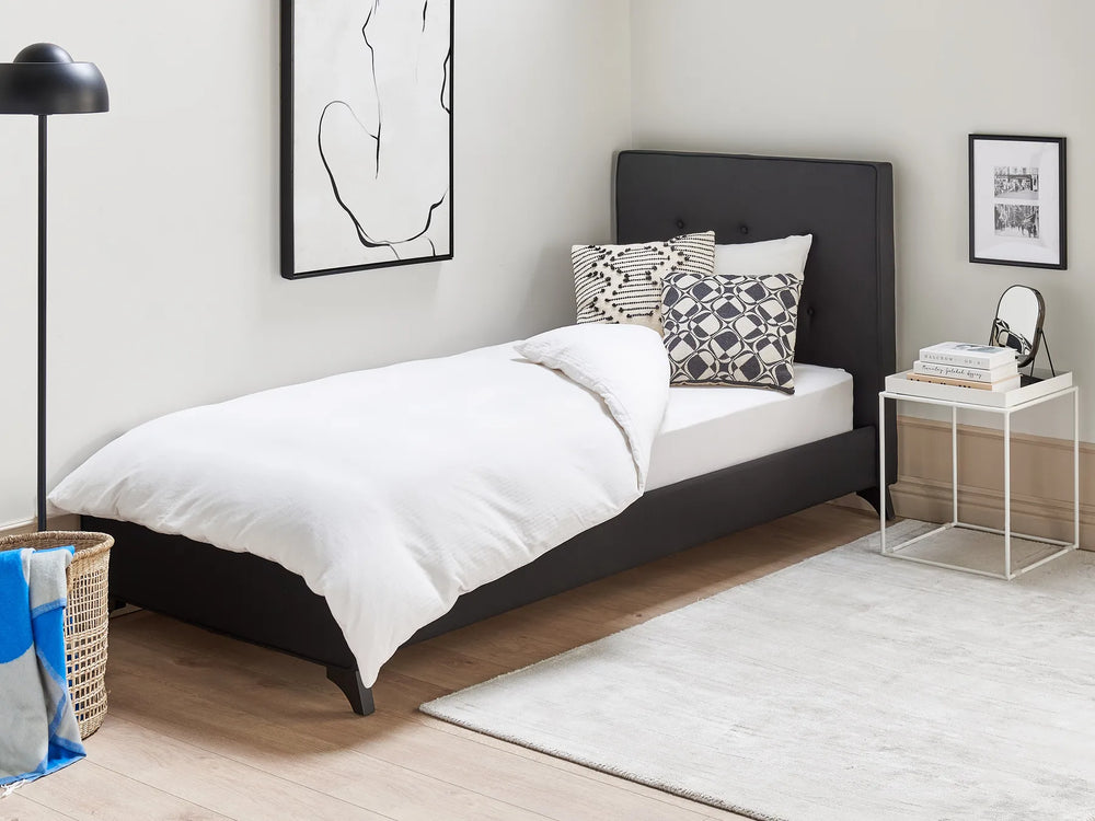 Modern bedroom with a black bed, white bedding, and decorative pillows.