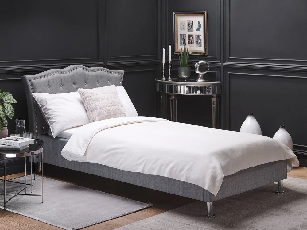 Gray upholstered bed with white bedding in a stylish bedroom setting.