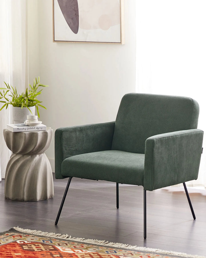 Green armchair in a room with a side table and plant