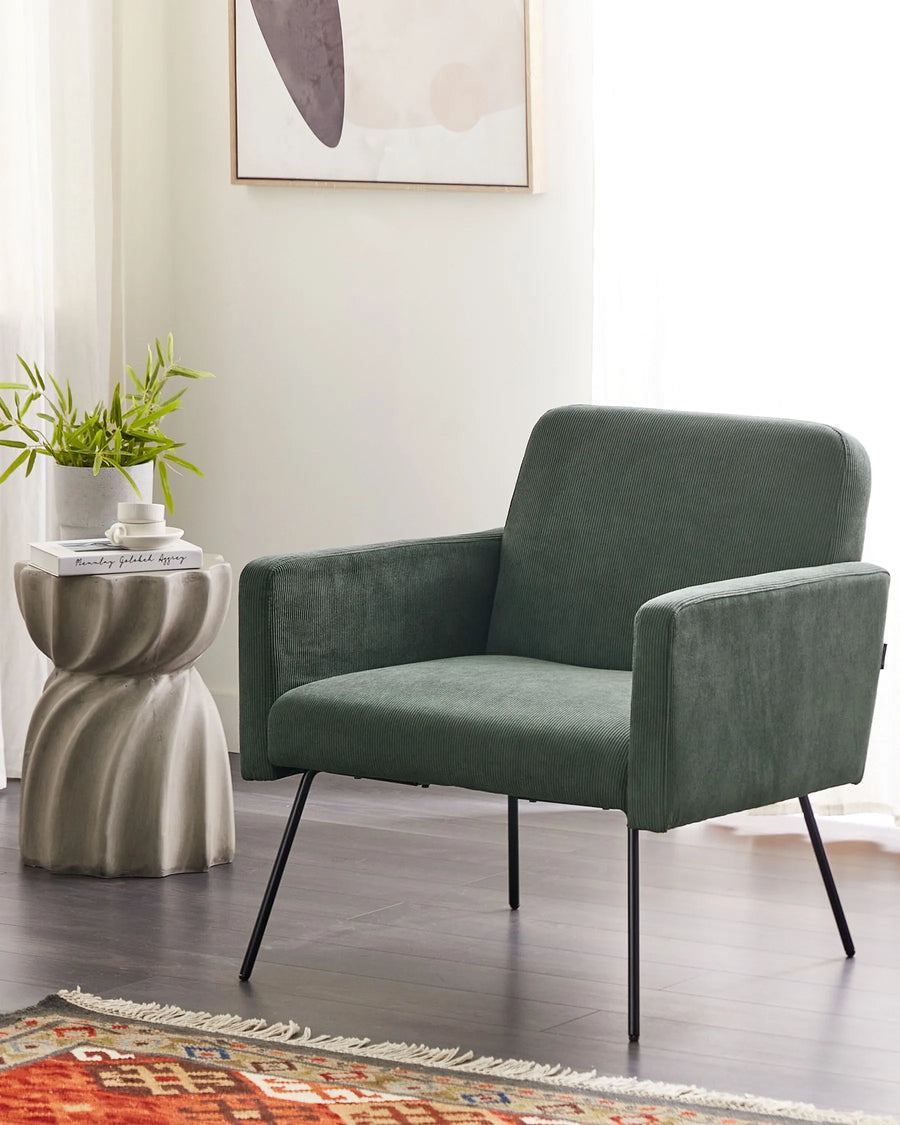 Green armchair in a room with a side table and plant