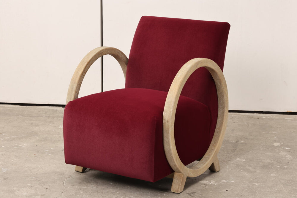 Red armchair with wooden armrests on a gray floor.