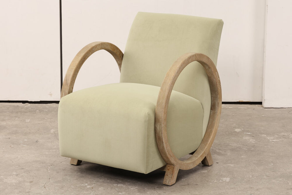 Light green armchair with wooden armrests on a gray floor.