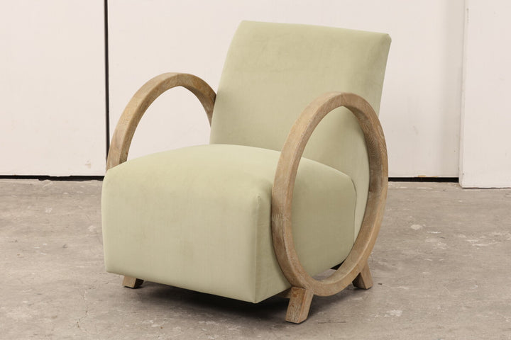 Light green armchair with wooden armrests on a gray floor.
