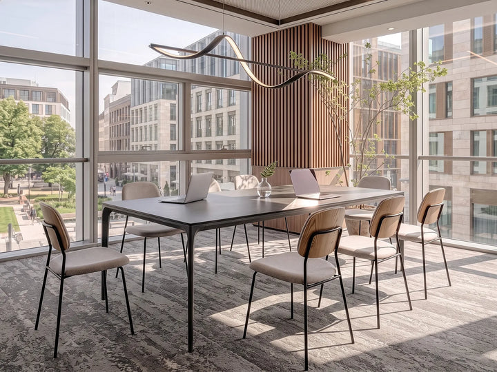 A modern meeting room setup featuring a long rectangular dark wood conference table surrounded by eight chairs with beige upholstered seats and black metal frames. The room is situated in a high-rise office with large floor-to-ceiling windows showing a city view, decorated with a curved black wall light and a vertical slatted wood accent wall.