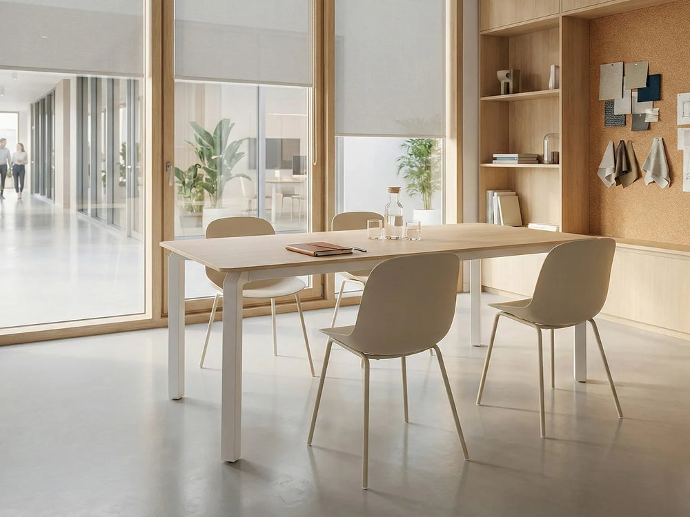 Modern office setting with a long white table and beige chairs in a bright room.