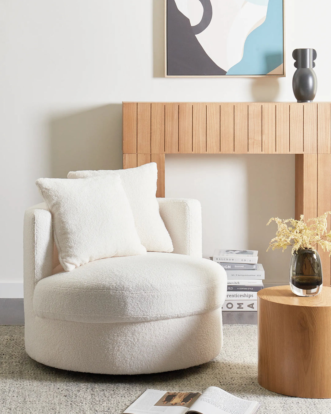 Beige armchair in a modern living room with wooden side table and abstract art on the wall.