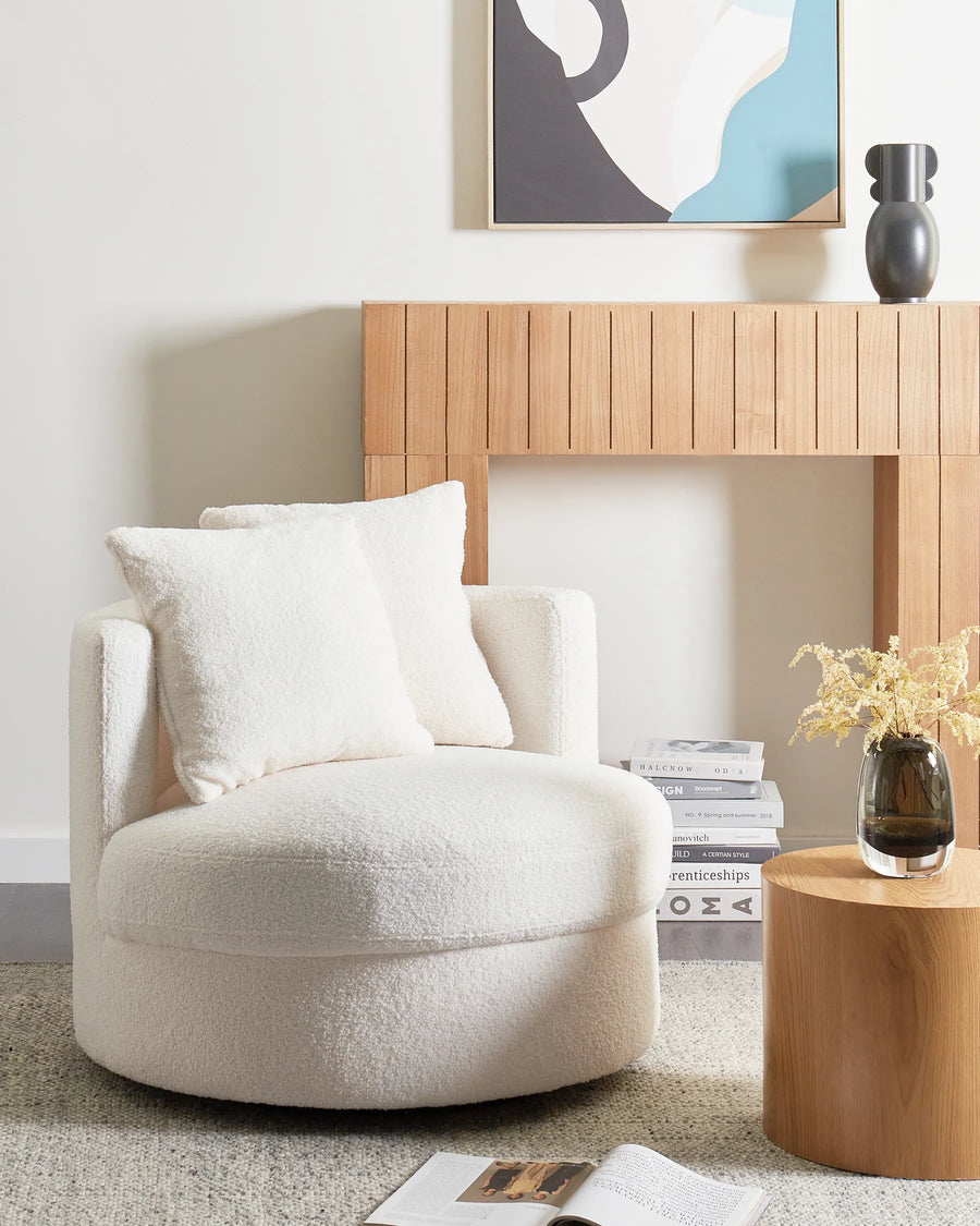 Beige armchair in a modern living room with wooden side table and abstract art on the wall.