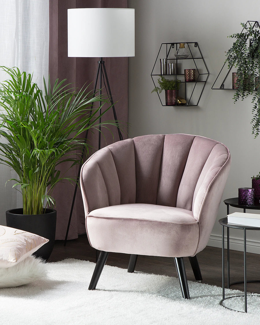 Pink armchair in a stylish living room with plants and decor.