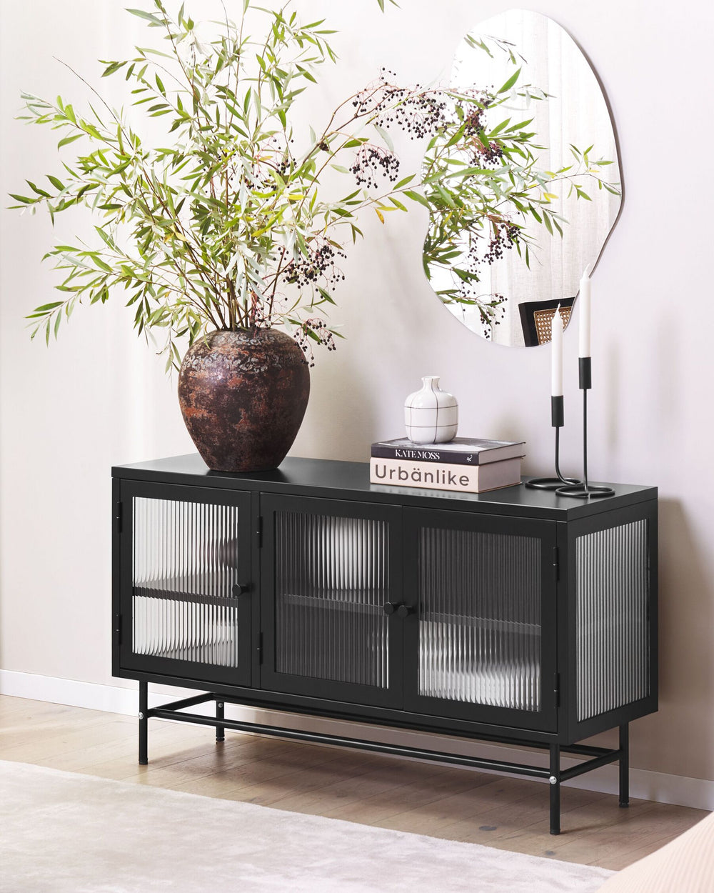 Black console table with decorative items including a vase and books against a white wall.
