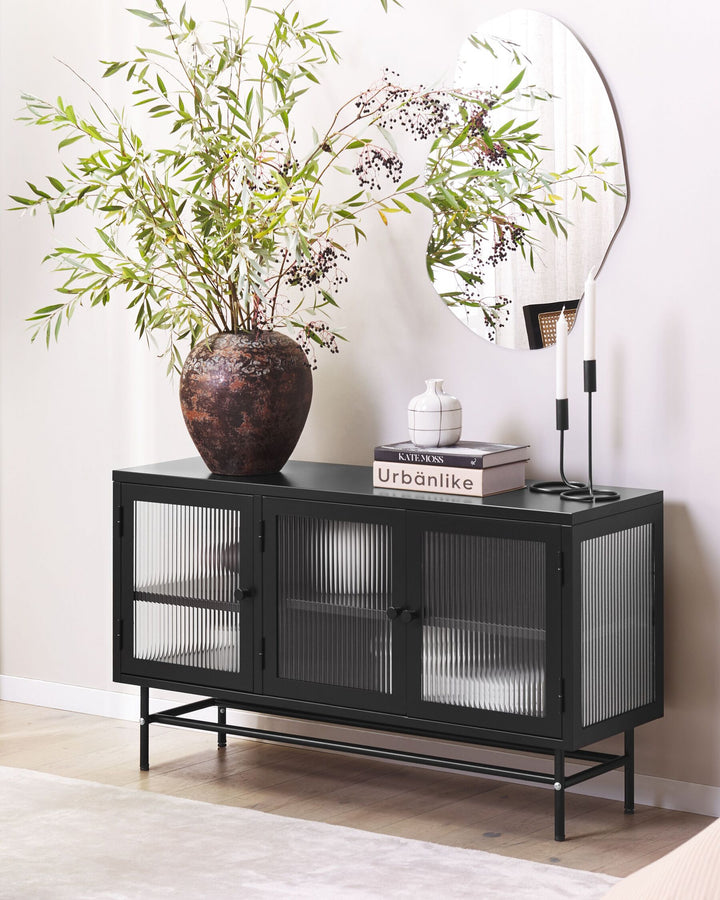 Black console table with decorative items including a vase and books against a white wall.